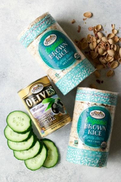 Sprouts Farmers Market organic rice cakes, can of black olives, sliced cucumbers and pistachio shells.