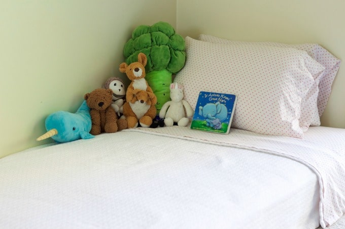 Children's bed with stuffed animals and a bedtime book.
