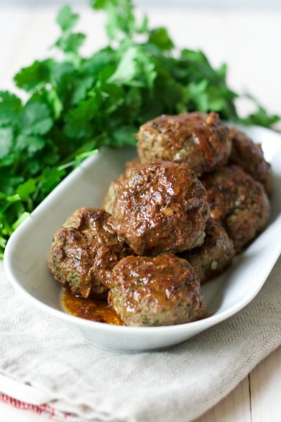 Stacked meatballs on a plate with fresh herbs.