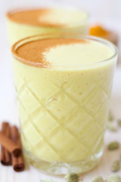 Glasses of golden milk smoothies with cinnamon dusted on the top.