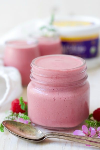 Jars of pink raspberry smoothies with fresh raspberries, flowers and a container of Nancy's organic whole milk cottage cheese.