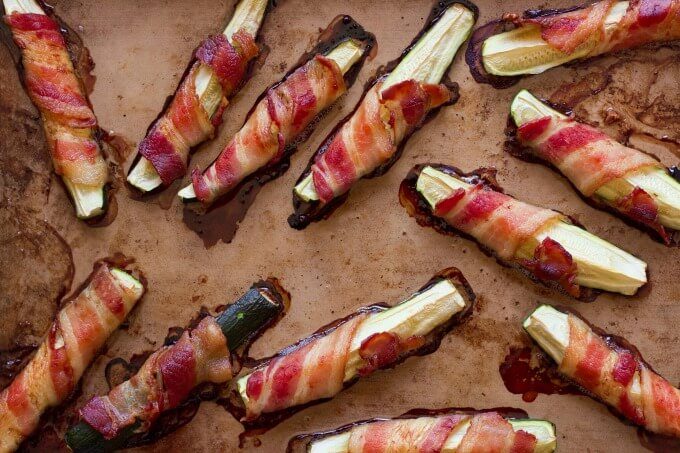 Bacon wrapped zucchini on a baking pan.